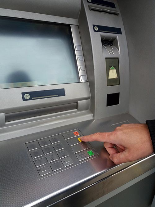 Man's using the ATM machine with cash cards.